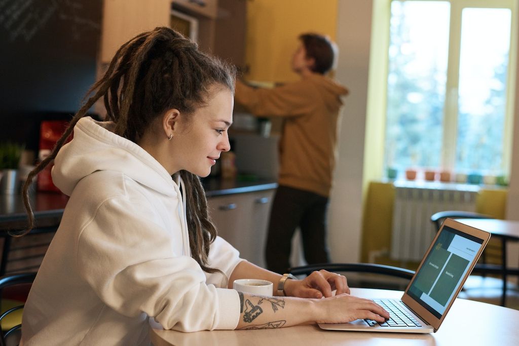 Une fille dans un bureau sur son ordinateur portable cherche des informations pour devenir indépendante à titre complémentaire