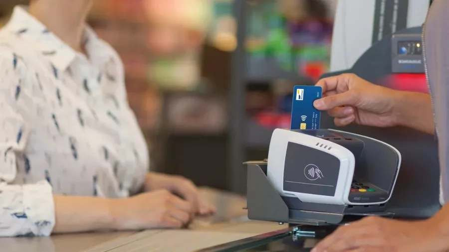 Une commerçante belge utilise un terminal de paiement Bancontact relié à son modem VOO business