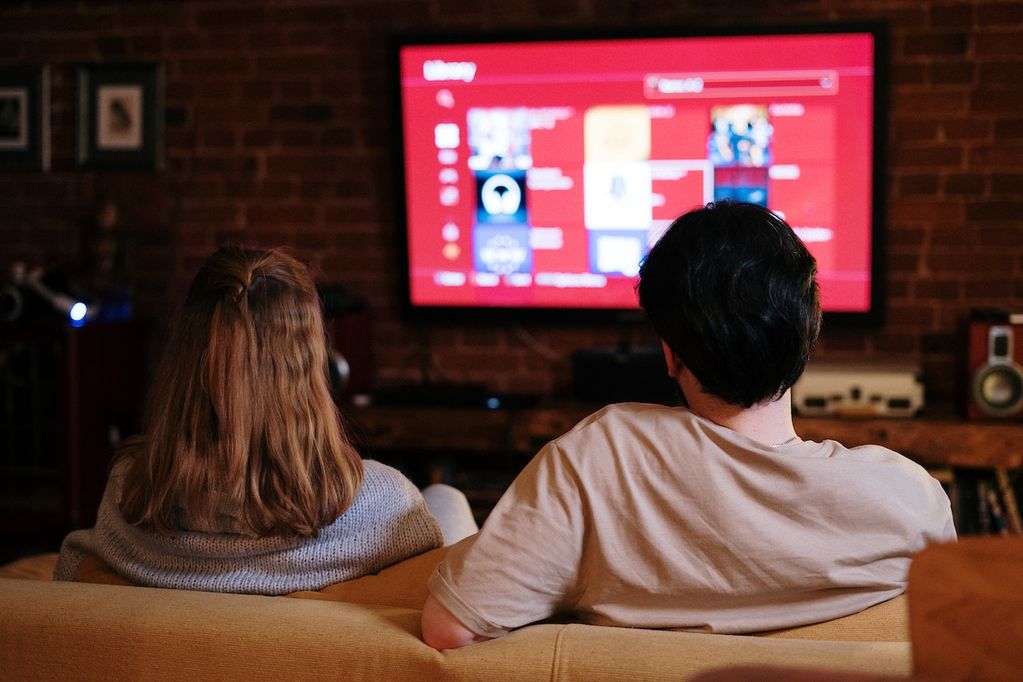 Un couple regarde l'un des 10 films à voir dans sa vie dans son canapé à la maison avec le décodeur de VOO de TV numérique