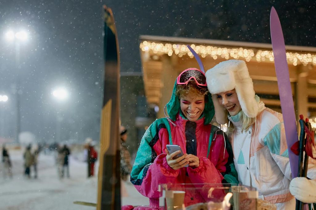Deux femmes aux sports d'hiver profitent du roaming gratuit de VOO mobile